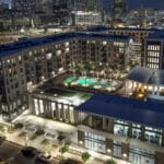 Modern apartment complex with illuminated pool at night.